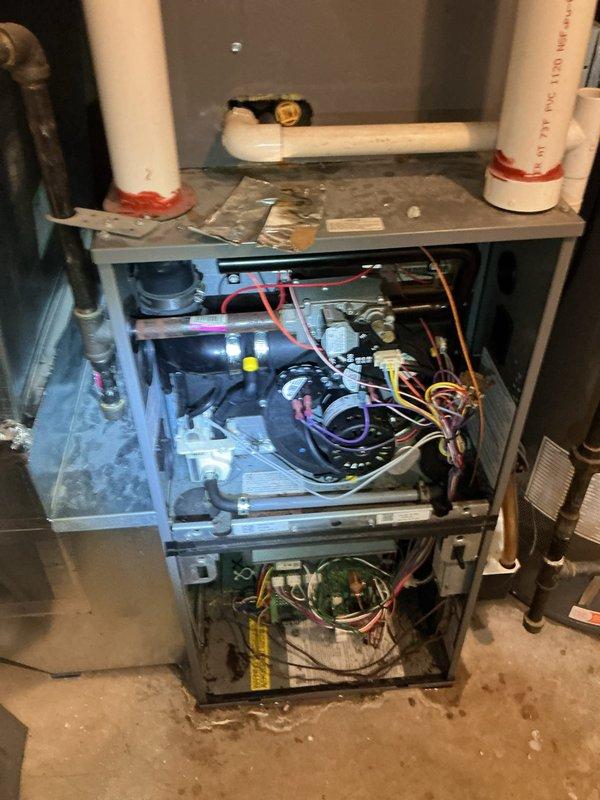 Responded to water leak complaint with unknown source affecting residential property. Upon investigation, inspected HVAC furnace system, condensate drainage lines, and plumbing infrastructure in basement utility area. Examined furnace unit with exposed internal components, including blower motor assembly, circuit board, and PVC condensate drain piping with red couplings. Investigated crawlspace area and floor joist cavities, inspecting various water supply lines, drain pipes, and potential leak sources. Observed discoloration and staining on wooden structural members and around plumbing penetrations indicating moisture intrusion. Assessed multiple potential leak sources including AC condensate drainage system, bathtub deck area, and HVAC equipment. Documented conditions with photographic evidence showing furnace components, condensate piping configuration, and crawlspace plumbing infrastructure. Determined leak source exceeded scope of plumbing-only repair and required HVAC specialist 