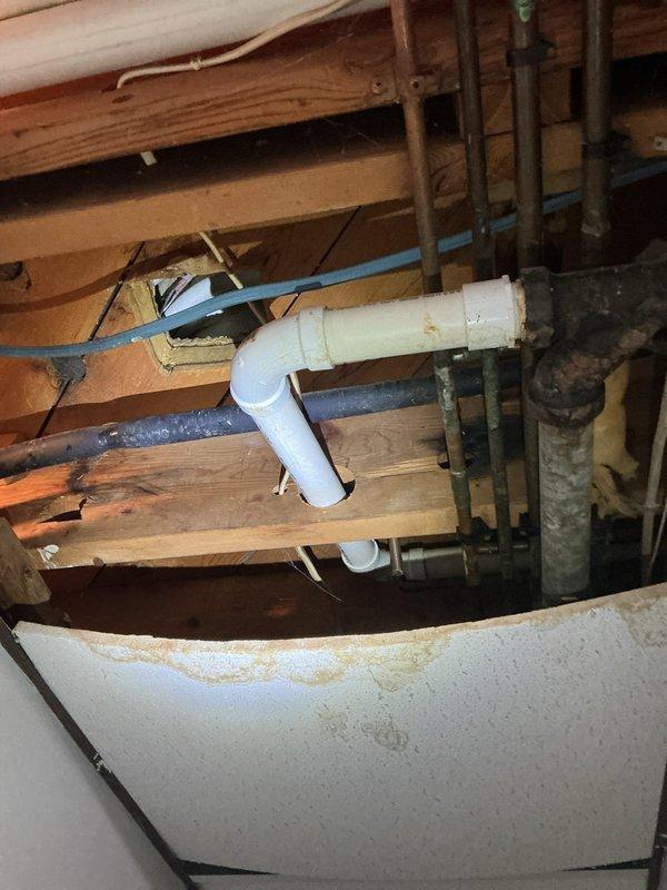 Responded to water leak complaint with unknown source affecting residential property. Upon investigation, inspected HVAC furnace system, condensate drainage lines, and plumbing infrastructure in basement utility area. Examined furnace unit with exposed internal components, including blower motor assembly, circuit board, and PVC condensate drain piping with red couplings. Investigated crawlspace area and floor joist cavities, inspecting various water supply lines, drain pipes, and potential leak sources. Observed discoloration and staining on wooden structural members and around plumbing penetrations indicating moisture intrusion. Assessed multiple potential leak sources including AC condensate drainage system, bathtub deck area, and HVAC equipment. Documented conditions with photographic evidence showing furnace components, condensate piping configuration, and crawlspace plumbing infrastructure. Determined leak source exceeded scope of plumbing-only repair and required HVAC specialist 