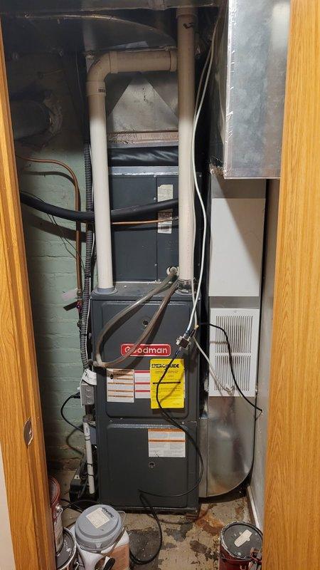 Responded to no cooling complaint on 14-year-old Goodman system with reported hissing noise from indoor unit during AC operation. Upon arrival, diagnosed high head pressure on R410A system with abnormal hissing sound originating from furnace area. Performed system evaluation including condenser coil inspection, which showed acceptable cleanliness, and verified air filter condition was satisfactory. Testing revealed blockage in refrigerant line causing restricted flow and elevated discharge pressure. Documented findings with photos of indoor Goodman furnace unit and outdoor condensing unit. Presented repair options to address refrigerant line restriction and advised customer that comfort advisor would follow up regarding comprehensive repair estimate given home warranty coverage.