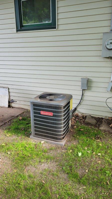 Responded to no cooling complaint on 14-year-old Goodman system with reported hissing noise from indoor unit during AC operation. Upon arrival, diagnosed high head pressure on R410A system with abnormal hissing sound originating from furnace area. Performed system evaluation including condenser coil inspection, which showed acceptable cleanliness, and verified air filter condition was satisfactory. Testing revealed blockage in refrigerant line causing restricted flow and elevated discharge pressure. Documented findings with photos of indoor Goodman furnace unit and outdoor condensing unit. Presented repair options to address refrigerant line restriction and advised customer that comfort advisor would follow up regarding comprehensive repair estimate given home warranty coverage.