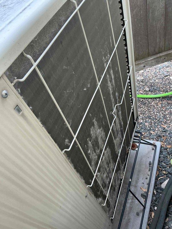 Responded to water leakage issue on Mitsubishi ductless mini-split system where condensate was dripping inside from the indoor air handler. Upon inspection, found water accumulation behind the filter not draining properly, with moisture dripping through the cooling fins while system remained operational. Addressed the leaking head unit by clearing the condensate drain line obstruction. Performed thorough cleaning of the refrigerant line set and outdoor condenser unit, which exhibited significant dirt, dust, and debris accumulation across the coil fins and surfaces affecting system efficiency.