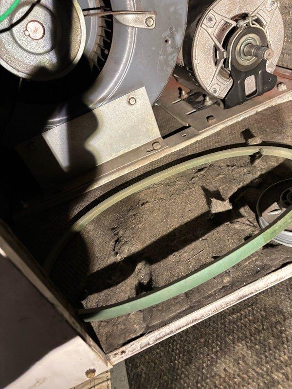Responded to no cooling complaint on approximately 15-year-old split system. Upon inspection, discovered air handler equipped with heating coil supplied by Munchkin boiler and separate A/C coil for cooling. Found blower pulley had completely sheared off, resulting in loss of airflow and subsequent freezing of indoor evaporator coil. Exterior condensing unit identified as 1994 Trane unit utilizing R-22 refrigerant, which tested critically low on charge. Evaporator coil exhibited heavy dust and debris accumulation due to inadequate filtration maintenance. System currently inoperable due to dual failures: mechanical failure of blower assembly and significant refrigerant loss in outdoor unit. Documented conditions with photographs showing failed blower pulley assembly and contaminated coil surfaces. Advised homeowner that both airflow restoration and refrigerant system repair required before normal operation can resume. Customer requested pricing for blower motor repair and full replacemen