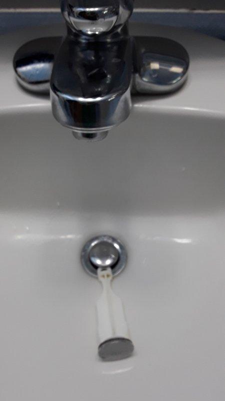 Responded to service call for non-functioning bathroom sink stopper. Upon inspection, diagnosed failed pop-up drain linkage assembly preventing stopper operation. Documented existing chrome cross-handle faucet and drain configuration with photos. Provided estimate for complete lavatory faucet replacement to resolve linkage failure.