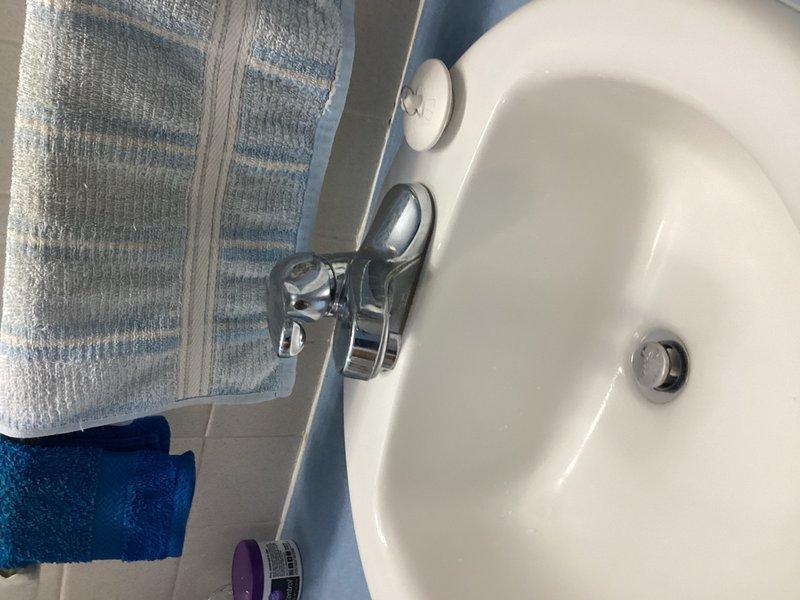 Responded to service call for non-functioning bathroom sink stopper. Upon inspection, diagnosed failed pop-up drain linkage assembly preventing stopper operation. Documented existing chrome cross-handle faucet and drain configuration with photos. Provided estimate for complete lavatory faucet replacement to resolve linkage failure.