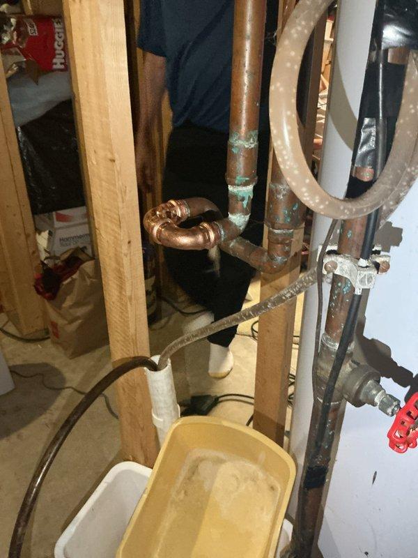 Responded to emergency call for leaking water softener system in basement utility area. Upon arrival, found water softener experiencing severe leakage from multiple points on the control head assembly, with active water discharge requiring immediate attention. Assessed unit condition and determined repair was not viable due to extent of deterioration and corrosion on copper piping connections. Bypassed the water softener system to restore water flow to the residence and prevent further water damage. Completely removed the failed water softener unit from the plumbing system. Documented existing plumbing infrastructure including copper supply lines, PVC drainage, and water heater connections. Provided detailed estimate for installation of customer-supplied replacement water softener unit.