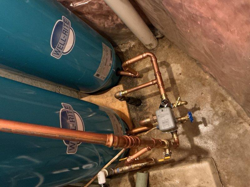 Completed comprehensive repipe of water softener system including installation of three-zone bypass configuration with tank tee assemblies for dual pressure tank setup. Replaced existing piping and valves throughout the system to accommodate proper flow management. Added check valve to geothermal feed line to prevent backflow and protect system integrity. Reconfigured all copper piping connections to pressure tanks and installed new three-valve bypass assembly for water softener operation. System was pressure tested and inspected for leaks with all components functioning properly upon completion.