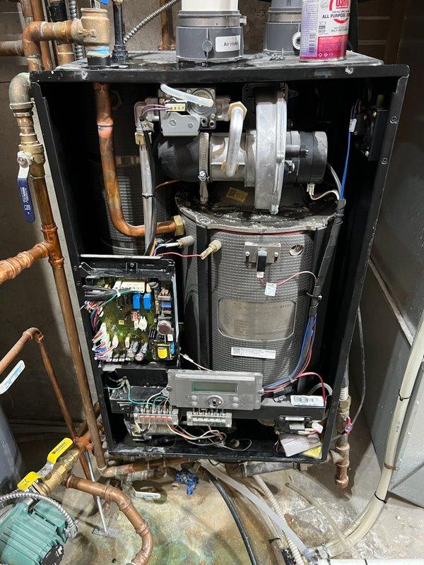 Responded to no hot water call on Westinghouse Premium boiler less than 10 years old. Found unit completely inoperative with tripped breaker caused by slow leak from top-mounted air bleeder valve that dripped water into internal components, shorting out electrical system. Drained system completely and replaced failed air bleeder valve assembly. Replaced damaged circuit board and control components that sustained water damage from leak. Refilled system, purged air from lines, and restored unit to full operation with hot water service confirmed.