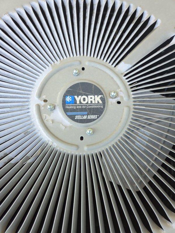 Performed comprehensive AC tune-up on York Stellar Series system. Upon inspection, discovered multiple issues requiring attention: blower wheel exhibiting excessive play, run capacitor reading 4.3uf against specification of 7.5uf, evaporator coil nearly completely blocked with debris, and outdoor contactor showing signs of pitting with low resistance reading of approximately 10 ohms. Air filter found in clean condition. Conducted routine electrical inspection of outdoor condensing unit with all other components testing within acceptable parameters. System operational testing revealed adequate performance with 20-degree temperature split across evaporator coil. Measured refrigerant pressures indicated low charge, potentially affected by restricted evaporator coil but more likely due to actual refrigerant loss given continued cooling performance. Recommended obtaining estimates for evaporator coil cleaning, contactor replacement, and blower motor replacement. Also advised considering sys