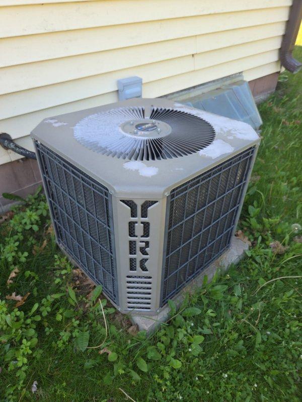 Performed comprehensive AC tune-up on York Stellar Series system. Upon inspection, discovered multiple issues requiring attention: blower wheel exhibiting excessive play, run capacitor reading 4.3uf against specification of 7.5uf, evaporator coil nearly completely blocked with debris, and outdoor contactor showing signs of pitting with low resistance reading of approximately 10 ohms. Air filter found in clean condition. Conducted routine electrical inspection of outdoor condensing unit with all other components testing within acceptable parameters. System operational testing revealed adequate performance with 20-degree temperature split across evaporator coil. Measured refrigerant pressures indicated low charge, potentially affected by restricted evaporator coil but more likely due to actual refrigerant loss given continued cooling performance. Recommended obtaining estimates for evaporator coil cleaning, contactor replacement, and blower motor replacement. Also advised considering sys
