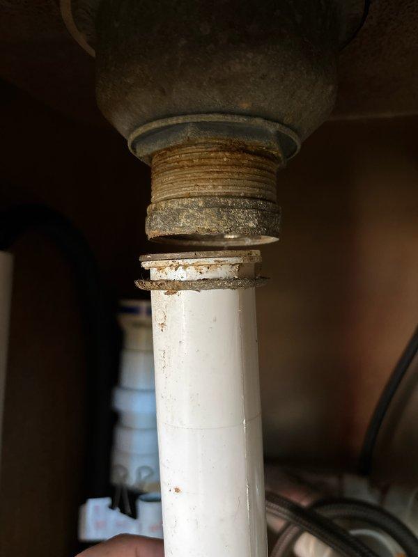 Responded to kitchen sink drain failure where the tailpiece assembly had separated from the basket strainer connection. Upon inspection, found the threaded pipe connection had failed due to age-related corrosion on the metal fittings, though the tailpiece itself remained in serviceable condition. Replaced the corroded nut and threaded connection components leading to the basket strainer while retaining the existing tailpiece. Reassembled the drain assembly, ensuring proper alignment with the existing P-trap configuration and garbage disposal connection. Tested the system for leaks and verified proper drainage function before completing the repair.