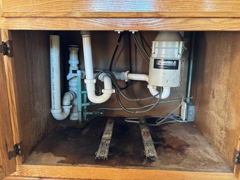 Responded to kitchen sink drain failure where the tailpiece assembly had separated from the basket strainer connection. Upon inspection, found the threaded pipe connection had failed due to age-related corrosion on the metal fittings, though the tailpiece itself remained in serviceable condition. Replaced the corroded nut and threaded connection components leading to the basket strainer while retaining the existing tailpiece. Reassembled the drain assembly, ensuring proper alignment with the existing P-trap configuration and garbage disposal connection. Tested the system for leaks and verified proper drainage function before completing the repair.