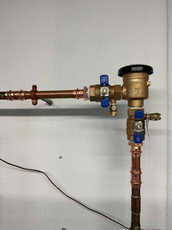 Responded to service call for leaky outdoor shut-off valve on irrigation system. Upon inspection, diagnosed failed ball valve within the irrigation vacuum breaker assembly. Removed defective vacuum breaker and installed new replacement unit with brass fittings and blue-handled ball valves to restore proper operation and eliminate leak.
