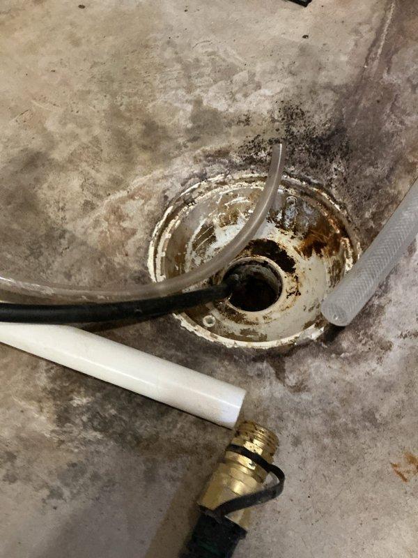 Responded to mechanical room floor drain backup occurring during laundry use. Verified customer concern and traced drainage system configuration. Identified that both floor drain and laundry drain discharge into a sewage ejection pump/lift station assembly. Inspected ejection pump tank and found it filled to capacity with wastewater. Diagnosed pump failure as root cause of drainage backup. Documented pump malfunction with photographic evidence showing corroded drain assembly, accumulated sediment, and pump components including actuator stem and discharge piping. Referred job to licensed plumbing contractor for pump repair or replacement as no corrective work was performed during diagnostic visit.
