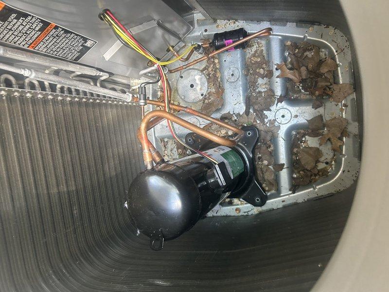 Responded to warranty call for recently installed condenser unit. Upon inspection, discovered compressor was not secured to mounting pad and refrigerant lines were bent, preventing proper installation of mounting bolts. Additionally found service valve caps missing from both ports. Documented conditions with photographs showing unsecured compressor, bent copper lines, debris accumulation in unit base, and exposed service valves. Unit currently operational but requires follow-up visit to properly secure compressor, straighten or replace refrigerant lines as needed, and install proper service valve caps. Submitted work order for corrective action and scheduled callback with customer.
