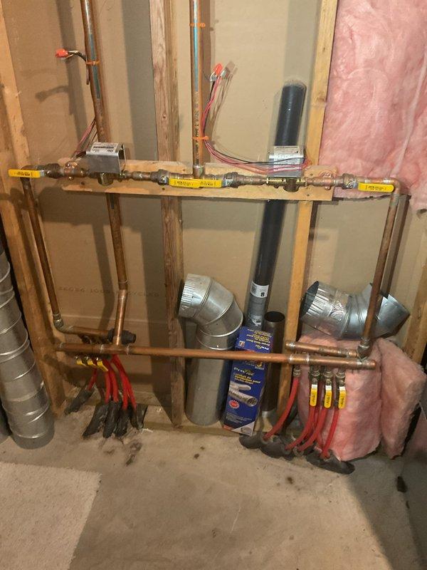 Conducted comprehensive assessment of whole-home in-floor radiant heating system experiencing multiple leaks at manifold connections and zone valves. Identified necessary repairs including replacement of T-fitting in bedroom ceiling and basement, three-port manifold replacement near air handler, and one Erie zone valve. Recommended upgrading expansion tank to 30-gallon capacity with wall relocation and proper strapping, installation of new pressure relief valve and automatic air vent, and complete boiler maintenance service with cleaning. Documented existing conditions with photographs showing copper manifold distribution system with PEX tubing connections, multiple zone valve assemblies, and current expansion tank configuration. Project scope transferred to plumbing department for formal estimate preparation due to extent of hydronic system repairs required.