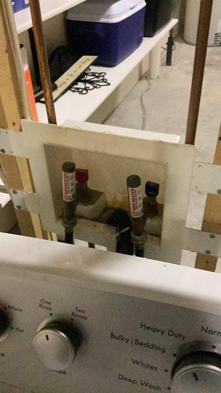 Responded to non-functioning washing machine shut-off valves that were experiencing leaks. Replaced both defective boiler drain-style shut-off valves with new brass quarter-turn ball valves featuring blue handles, installed in recessed wall box between studs. Both valves were connected to existing copper supply lines serving the laundry area, restoring proper water control and eliminating leaks.