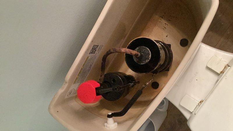 Completed comprehensive plumbing inspection of residential property. Inspected toilet tank internal components, noting functional flush mechanism with flapper valve and float assembly in working condition; observed mineral deposit buildup on tank interior surfaces typical of normal wear. Examined shower plumbing fixtures including handheld shower hose assembly and chrome wall mounting bracket, confirming proper installation and operational condition.