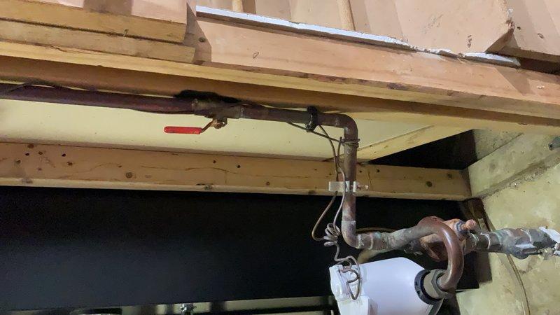 Responded to a water main leak at the residential property. Upon inspection, identified a slow drip originating from a corroded ball valve and coupling assembly located on the main water line prior to the water meter and main shut-off valve. The leak had been present for approximately two years. The plumbing infrastructure showed significant age-related deterioration, with extensive rust and corrosion visible on the brass valve body and copper pipe connections. Documented the condition of the aging plumbing system, including the corroded valve assembly and mixed materials from previous repairs. Explained that water service would need to be shut off from the exterior supply line to properly address the leak, as the affected components are positioned upstream of the interior shut-off valve. Provided the customer with multiple repair options to resolve the leak and prevent further deterioration of the water supply system.