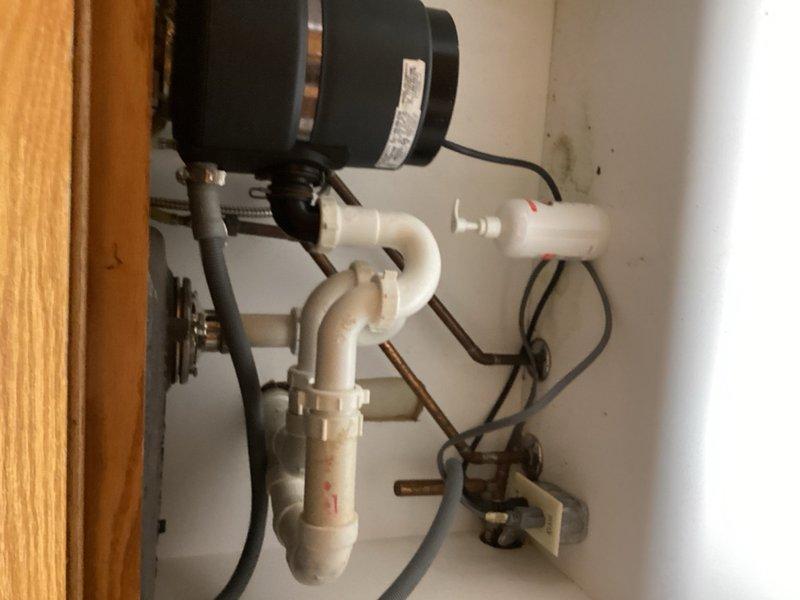 Responded to plumbing service call for multiple issues including leaking copper pipe above washing machine and slow bathroom drain. Upon inspection, identified leak in basement area and deteriorated drain pipe in wall from kitchen. Assessed sump pump assembly with PVC piping configuration showing signs of age and discoloration. Evaluated exposed plumbing infrastructure in unfinished basement area, including horizontal drain lines mounted to concrete block walls. Documented existing conditions of mechanical systems and drainage components. Provided estimate for replacement of compromised drain piping to resolve leak and drainage issues.