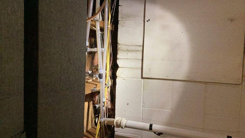 Responded to plumbing service call for multiple issues including leaking copper pipe above washing machine and slow bathroom drain. Upon inspection, identified leak in basement area and deteriorated drain pipe in wall from kitchen. Assessed sump pump assembly with PVC piping configuration showing signs of age and discoloration. Evaluated exposed plumbing infrastructure in unfinished basement area, including horizontal drain lines mounted to concrete block walls. Documented existing conditions of mechanical systems and drainage components. Provided estimate for replacement of compromised drain piping to resolve leak and drainage issues.