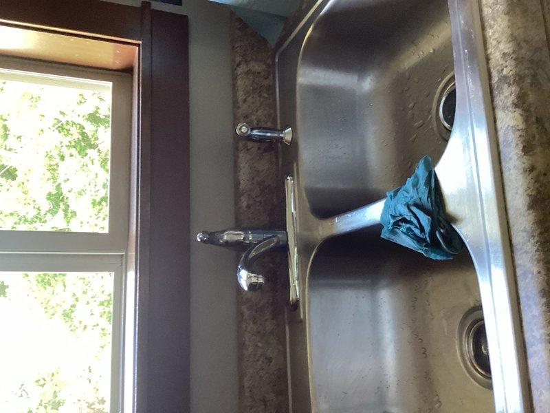 Responded to service call for kitchen plumbing issues involving a dripping faucet and leaking dishwasher. Upon inspection, identified active leak at faucet stem and water seepage from dishwasher door seal. Removed existing defective faucet fixture and installed new replacement unit to eliminate leak at sink. Advised homeowner to contact appliance specialist regarding dishwasher replacement due to door seal failure. Documented completed installation with photos of work area.