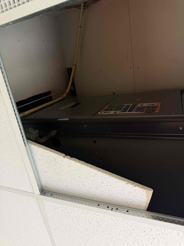 Responded to no cooling complaint in front zone of building. Upon arrival, found thermostat blank and unresponsive. Diagnosed issue as access panel not fully secured, preventing door safety switch from engaging and cutting power to system. Repositioned access panel to ensure proper contact with door switch. System immediately restored power and resumed normal operation. Verified thermostat display returned and unit cycled on properly. Documented equipment condition via photos showing air handler compartment and internal components accessed during troubleshooting.