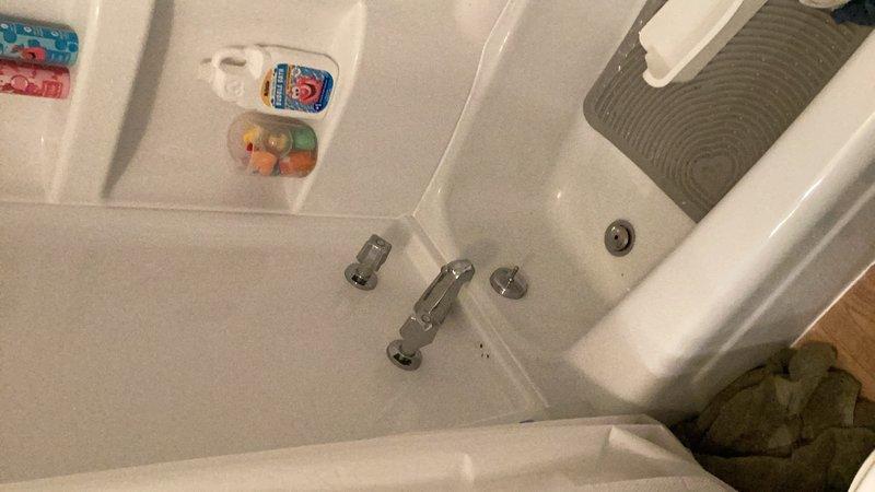 Responded to emergency plumbing call for active pipe leak behind shower wall causing water damage to basement below. Main water supply was shut off upon arrival to prevent further damage. Diagnosed hot water control issue at bathtub faucet where hot water valve failed to shut off completely. Accessed plumbing behind shower wall and replaced defective valve seat and washer assembly. Installed new ball valves on both hot and cold water supply lines feeding the shower to provide improved shutoff capability and facilitate future maintenance access. Tested all fixtures for proper operation and verified leak was resolved with no active water flow detected behind wall or into basement area.