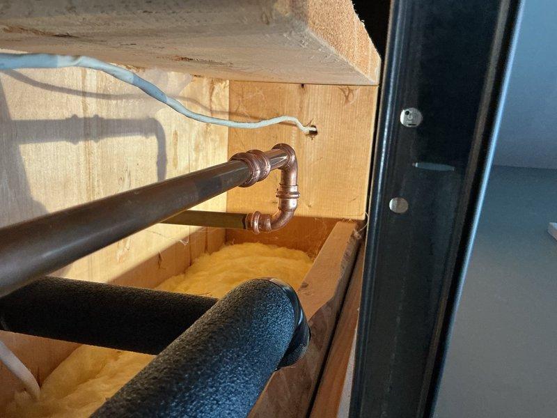 Responded to a water supply line leak in the basement ceiling affecting the upstairs kitchen sink. Upon inspection, identified a pinhole leak in the copper piping with corrosion present on two 90-degree elbow fittings, causing one drip every 10-20 seconds. The original copper plumbing dated back to the home's construction in 1999 and was accessible through the drop ceiling. Removed and replaced both corroded copper 90-degree elbows with new fittings. Restored water supply and performed leak verification to confirm repair integrity. System returned to full operation with no active leaks detected.