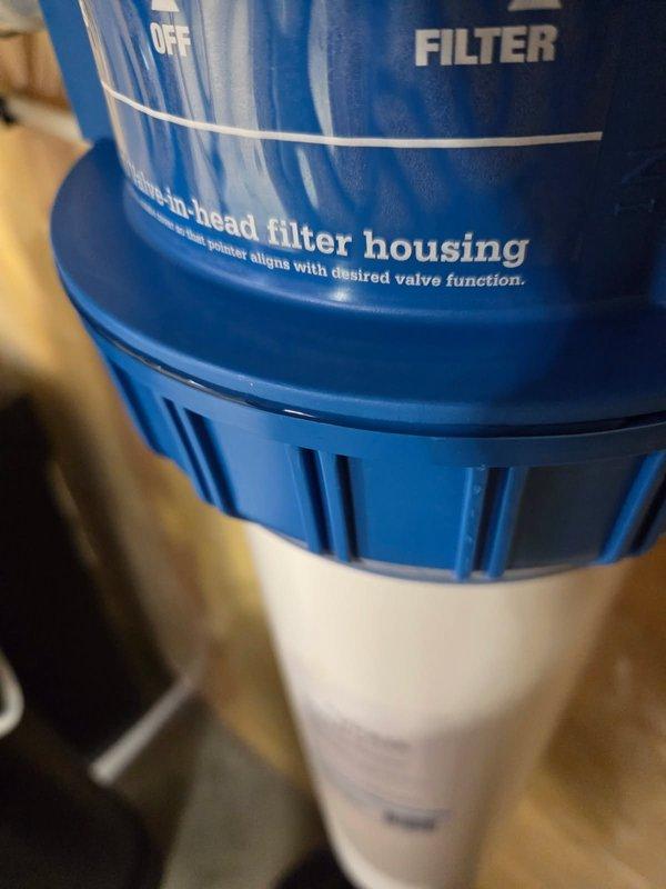 Responded to leak complaint on previously installed Jumbo Valve-in-head water filter housing system. Upon inspection, identified improper seal on filter canister causing water leakage. Removed and reinstalled filter housing unit, ensuring proper threading and O-ring seal between blue head assembly and white filter canister. Verified system operation through bypass, off, and filtration modes, confirming no active leaks and proper functionality upon completion.
