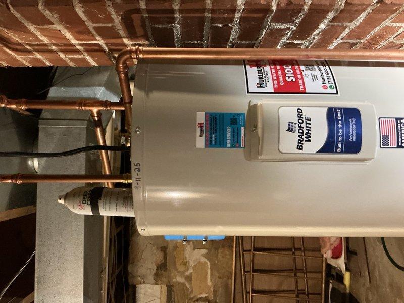 Responded to no hot water complaint on one-year-old Bradford White electric water heater following recent power outage. Performed electrical diagnostics and confirmed no power present at water heater unit despite customer's attempts to reset breaker. Traced electrical circuit from water heater back to upstream junction box and identified failed breaker tab in junction box preventing power transmission to unit. Verified incoming power to junction box was present but no power output to water heater circuit. Documented findings with photographs of installation and recommended licensed electrician to replace defective junction box component to restore power to water heater.