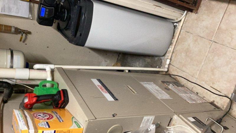 Responded to complaint of salty taste in water and excessive brine level in tank above salt line. Calculated cabinet volume and evaluated existing fill/draw cycle parameters based on 0.2 gpm draw rate and 0.5 gpm fill rate. Adjusted water softener regeneration cycle settings: increased backwash time from 5 minutes to 10 minutes, increased rapid rinse time from 5 minutes to 7 minutes, decreased draw time from 33 minutes to 21 minutes (approximately 4.2 gallons), and decreased fill time from 19 minutes to 7 minutes (approximately 3.5 gallons). Documented equipment with photos.