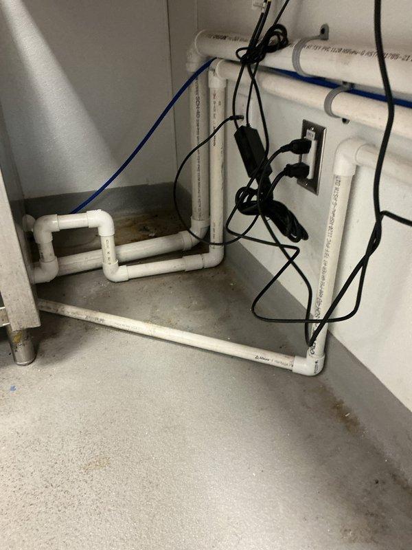 Supplied and installed all necessary piping and fittings to connect commercial espresso machine to building water supply and drain systems in compliance with Minnesota plumbing code. Installation included white PVC drain lines configured in proper U-trap formation and blue flexible water supply line with brass fittings secured to structural joists. All connections tested and verified operational with 1-year parts and labor warranty included.