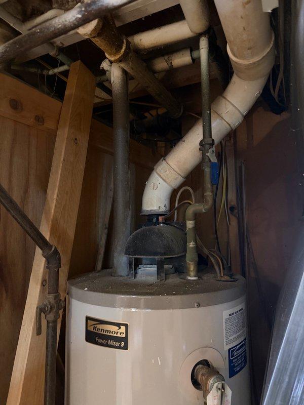 Completed comprehensive plumbing inspection of residential mechanical room, examining water heater installation, piping connections, and associated plumbing systems. Documented existing Kenmore Power Miser 9 water heater with power vent configuration, pressure relief components, and PVC/steel pipe routing for service records.