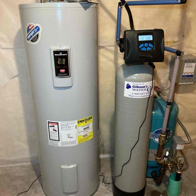 Completed comprehensive plumbing inspection including water quality testing of the residential water heating and treatment system. Inspected water heater, water softener/filtration equipment, and associated piping connections in basement utility area, documenting conditions with photographs. Provided detailed estimate for recommended repairs identified during inspection.