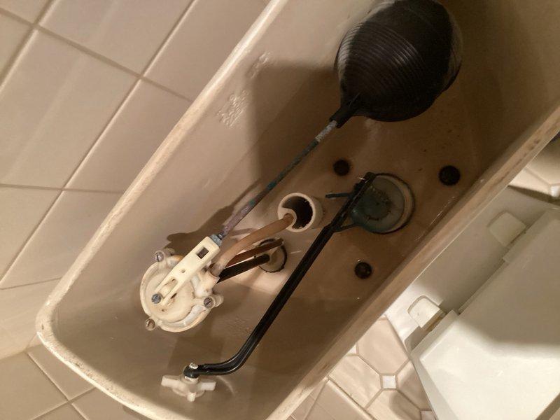 Conducted comprehensive plumbing assessment of bathroom fixtures including wall-mounted faucet assembly with separate hot and cold water control valves and toilet tank components. Documented existing conditions of chrome and brass-toned fixtures, identified mineral buildup on internal tank mechanisms, and photographed current state of installations for estimate preparation.