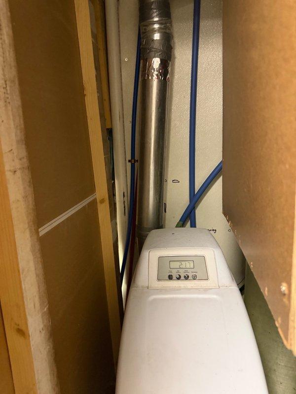 Responded to emergency call for active water heater leak causing water damage to surrounding floor area. Upon inspection, identified leak originating from bottom jacket of existing tanked water heater, indicating tank failure and requiring immediate replacement. Removed failed water heater unit and installed new tanked water heater in utility closet alongside existing water treatment equipment including water softener and well pressure tank system. Connected all supply and discharge plumbing lines, verified proper venting through existing metallic duct system, and tested unit operation to ensure proper heating function and confirmed no leaks at connections. Placed dehumidifier in area to assist with drying from previous water damage.