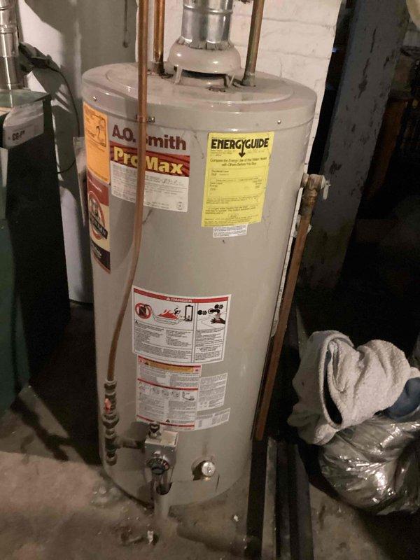 Responded to service call for inconsistent hot water production from an A.O. Smith ProMax tanked water heater over 20 years old. Upon inspection, confirmed unit was intermittently delivering hot and cold water, indicating heating element or thermostat failure consistent with age-related deterioration. Accessed unit through rear basement entrance and documented existing installation including copper supply piping, proximity to green boiler system with expansion tank, and overall mechanical room configuration. Recommended complete water heater replacement due to advanced age beyond typical service life and unreliable performance affecting household hot water availability.