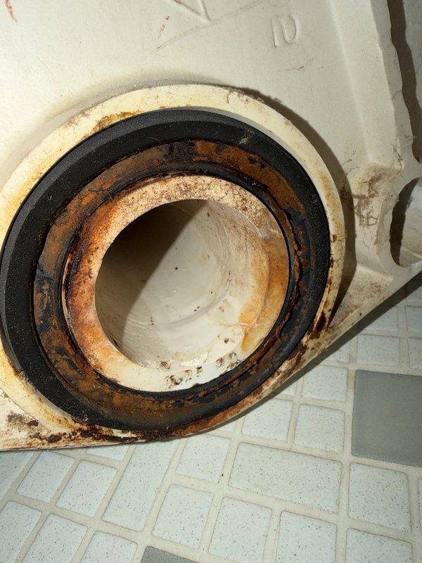 Responded to water leak complaint manifesting as ceiling stain on first floor below guest bathroom. Upon inspection, no visible water damage observed in guest bathroom itself. Removed wall-mounted toilet to access and inspect wax ring seal and flange connection. Inspection revealed corroded toilet flange with rust accumulation and deteriorated sealing components requiring replacement. Temporarily reset toilet to maintain facility function while awaiting replacement parts. Opened access point in plaster ceiling below to monitor for active leakage and verify source of water intrusion. Confirmed leak originated from compromised toilet seal at flange connection. Documented extensive corrosion on metal flange components and gasket deterioration through photographic evidence. Return visit scheduled to install new flange seal, permanently reset wall-mounted toilet, and repair plaster ceiling access opening upon parts arrival.