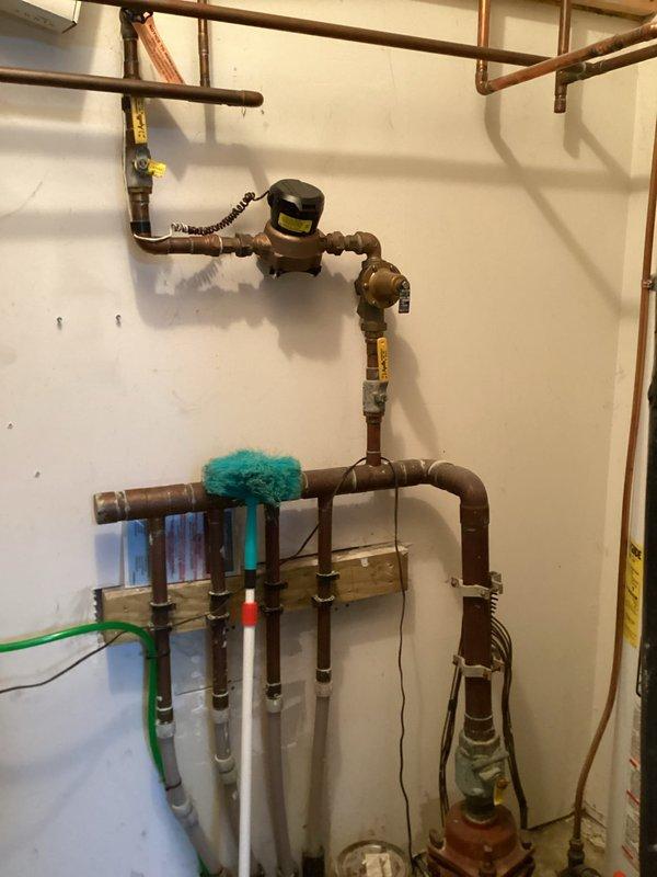 Responded to call for leaking water softener system. Upon inspection, found 20-year-old water softener actively leaking from top of unit and continuously filling. Identified that system lacked dedicated shut-off valve for isolation. Determined unit had reached end of serviceable life and required full replacement. Documented existing plumbing configuration including copper supply lines and connections to main water distribution system. Advised replacement of entire water softener unit due to age and condition of equipment.