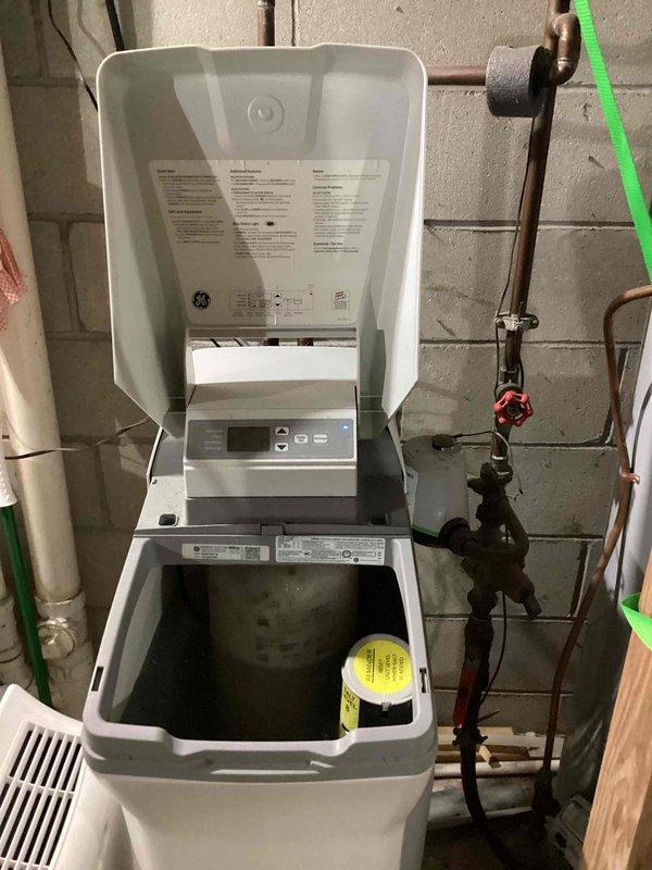 Replaced non-functional 15-year-old water softener system with new unit in basement utility area. The existing softener had ceased operation and was beyond economical repair, requiring complete replacement. Installed new water treatment system with digital control panel, connected to existing copper supply lines and drain plumbing, and verified proper operation of all functions.