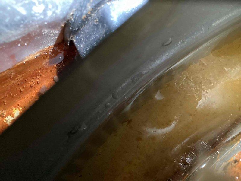 Responded to callback for water heater leaking from bottom of tank following recent installation. Upon inspection, confirmed active leak at base of RUUD residential water heater with water accumulating in catch pan. Documented leak location with photos showing moisture on copper connections and tank surface. Determined tank failure requiring complete water heater replacement to resolve issue.