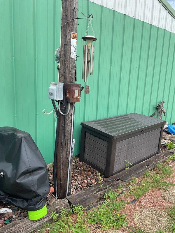 Responded to no-cooling complaint on approximately 35-year-old system where outdoor fan operates but compressor fails to start. Upon arrival, delayed initial inspection due to severe lightning and heavy rain for safety. After weather cleared, began diagnostic evaluation and discovered unit lacks proper disconnect switch at condenser, with unclear power shutoff location at pole-mounted electrical equipment. Observed evaporator coil freeze-up and oil residue on suction line indicating potential refrigerant leak. Unable to complete full diagnostic or repairs due to unsafe electrical configuration requiring licensed electrician to establish proper disconnect and verify power source before proceeding with compressor circuit testing. Recommended electrical service prior to HVAC repairs to address failed compressor start (suspected capacitor failure) and low refrigerant charge.