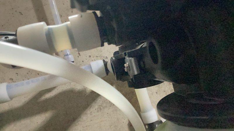 Responded to water leak at treatment tower system where both drain fittings were found cracked and failing. Removed and replaced both drain adapter fittings, re-taped PEX adapters to ensure proper seal, and noted that supply lines connecting to tanks may be under warranty from original installation. System tested and leak resolved.
