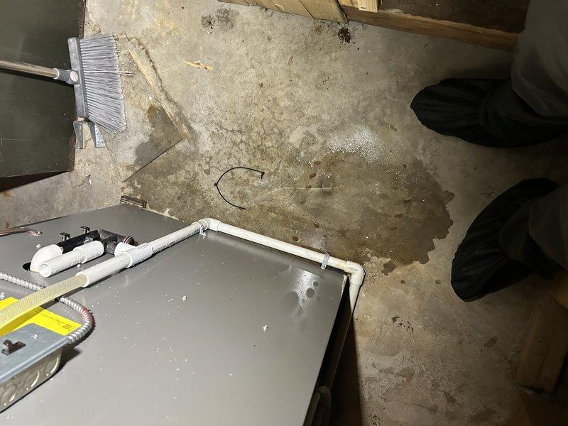 Responded to water leak complaint near furnace area. Upon inspection, identified multiple sources contributing to water accumulation: clogged air conditioner condensate drain line, sweating suction line causing condensation drip, and drain pipe displaced approximately one foot from floor drain opening. Cleared condensate drain obstruction and repositioned drain pipe to proper drainage location. Identified potential secondary leak in evaporator coil drain pan and noted water heater showing signs of leakage as separate issue. Performed complete system tune-up on HVAC equipment to ensure optimal operation. Documented conditions with photos showing supply duct temperatures, drain pan configuration, and floor water damage. Provided recommendations for water heater replacement and continued monitoring of coil drain pan condition.