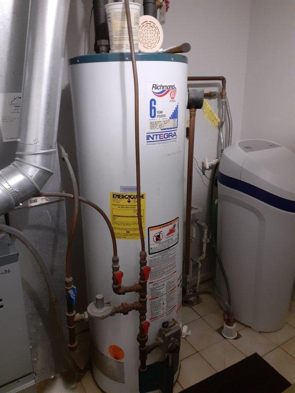 Conducted on-site assessment for water heater replacement options. Customer requested quote for heat pump water heater installation with preference for 40-gallon gas unit. Documented existing Richmond Integra 6-year warranty gas water heater installation, photographed current mechanical room configuration including furnace, water softener system, plumbing connections, and copper piping with shutoff valves for accurate replacement planning and specifications.