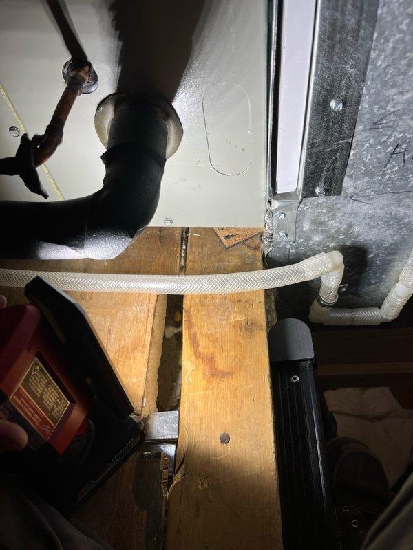 Responded to callback for water leakage from air handler in attic following previous drain line service. Upon inspection, discovered evaporator coil drain pan was improperly pitched, causing water to overflow from the backside after only 1.5 bottles of water. Corrected issue by lifting the return end of the air handler and installing additional support pads under both the unit and evaporator pan to achieve proper drainage slope. Verified repair by testing with two bottles of water, confirming proper drainage flow. Unit operating correctly with no further leakage. Photos documented completed work.