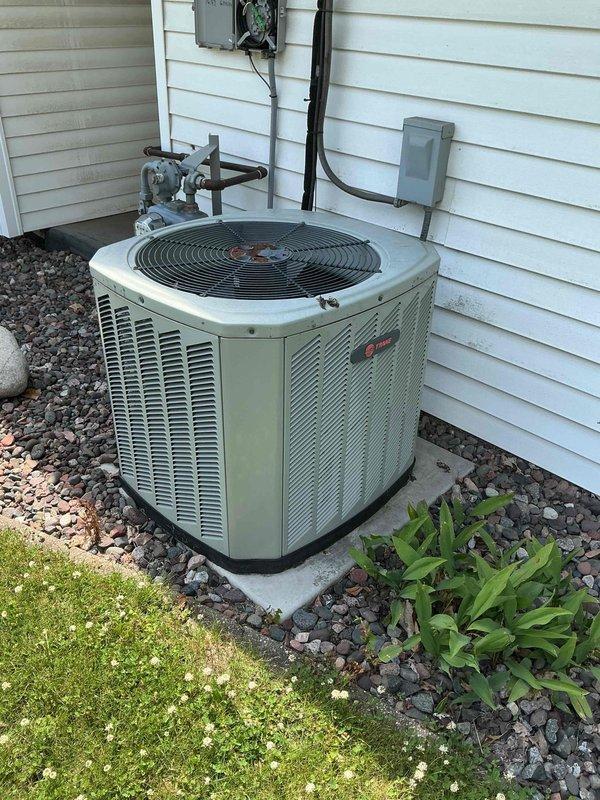 Responded to no cooling complaint on 14-year-old Trane air conditioning system. Upon arrival, found outdoor unit humming but condenser fan not operating. Performed diagnostic testing of electrical components and determined dual run capacitor had failed completely, preventing fan motor operation while compressor attempted to run. Replaced failed capacitor with new unit, rinsed down condenser coil and exterior components, reassembled unit, and verified proper system startup and operation. All components now functioning as designed with normal cooling restored.