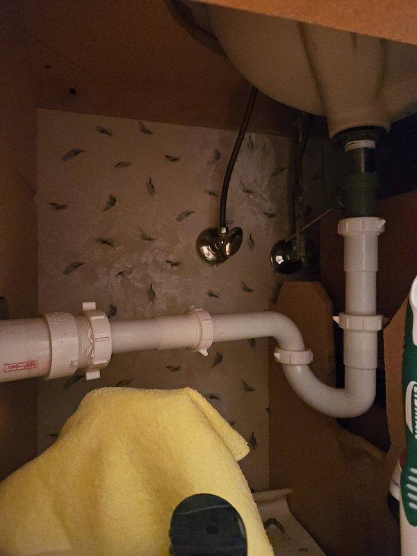 Responded to a bathroom vanity sink with a stuck pop-up drain stopper. Upon diagnostic inspection, determined that the trip lever assembly had become disconnected, allowing the stopper mechanism to lodge in the drain and prevent proper drainage. Removed the P-trap to gain access to the stopper from below and used a screwdriver to push the stopper upward through the drain opening for extraction. Reassembled the trip lever linkage and secured it with a rubber band behind the connection point to prevent future disconnection. Reinstalled the P-trap and tested the pop-up stopper assembly for proper operation. Verified full range of motion for opening and closing the drain stopper and confirmed no leaks at trap connections. System restored to full functionality.