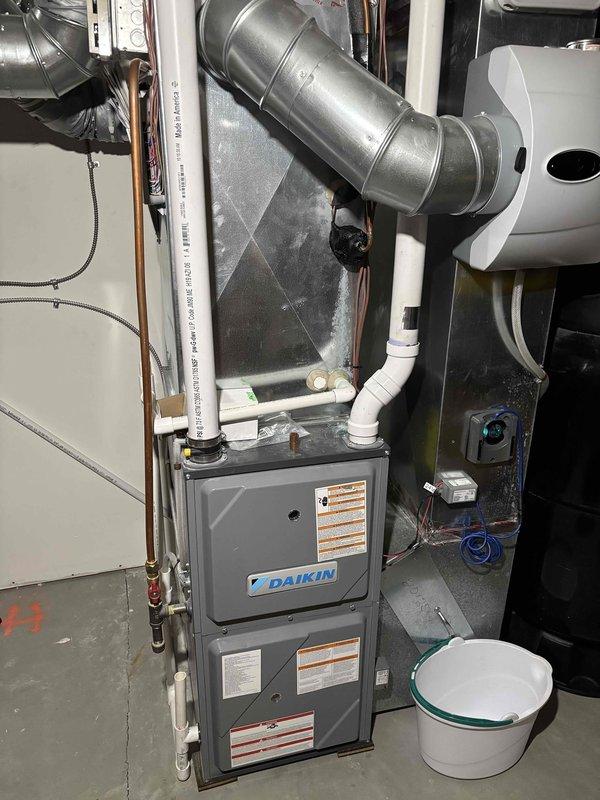 Completed routine AC tune-up maintenance on two Daikin condensing units with R-410A refrigerant at 72°F ambient temperature. Performed comprehensive inspection of both systems including filters, thermostats, temperature splits, condensers, evaporator coils, motors, capacitors, compressors, refrigerant levels, and condensate drains. Notable finding: one evaporator coil exhibited significant frost and ice buildup across entire A-frame surface, indicating potential airflow restriction, low refrigerant charge, or system malfunction requiring further diagnosis. All refrigerant lines, PVC drain lines, and electrical connections inspected. Both AC systems confirmed operational at completion of maintenance visit with all components functioning within normal parameters. Documentation photos captured of indoor air handler unit and frozen evaporator coil condition for service records.