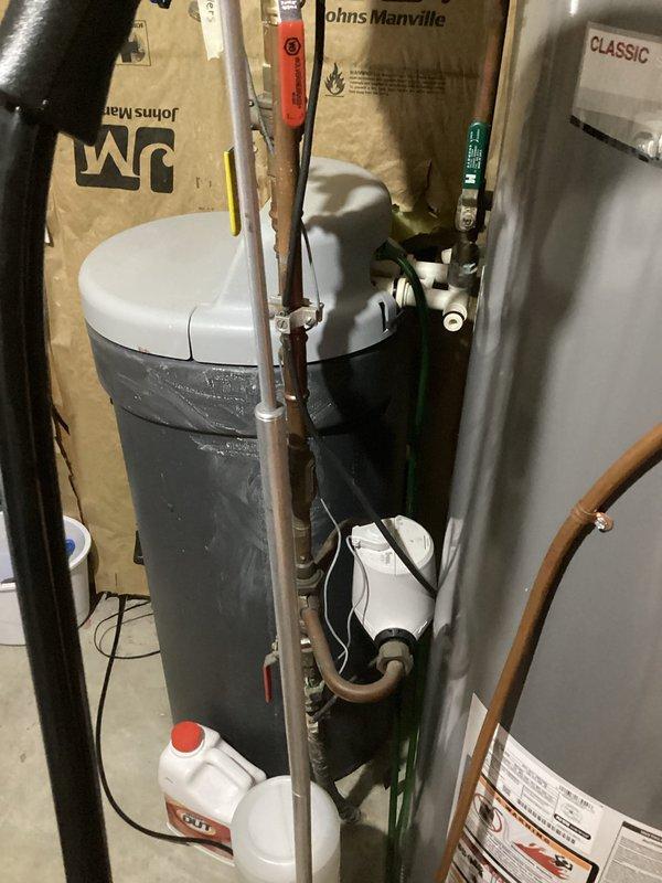 Responded to service call for non-functioning water softener unit that was over 10 years old. Upon inspection, determined that the existing gray cylindrical softener unit with moisture present on exterior had failed beyond economical repair due to age and condition. Recommended and discussed full system replacement with customer, as repair was not feasible given the unit's age and extent of deterioration.